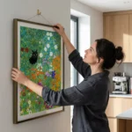 Woman hanging Klimt cat and mouse print in kitchen