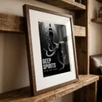 Framed black-and-white poster on a rustic shelf showing an octopus reaching for a bottle labeled 'RUM'; text reads 'DEEP SPIRITS' and 'Bottled Under Pressure'.