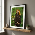 Framed green Jules et Jim poster on a wooden shelf beside a small vase and a succulent plant.