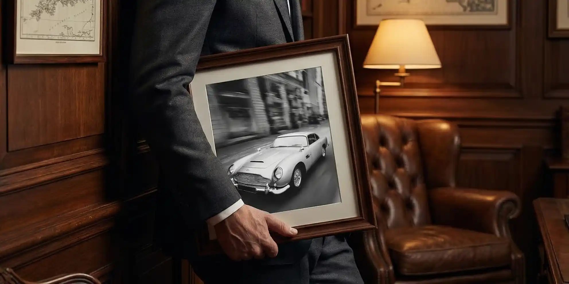 Man holding Aston Martin DB5 print in a frame.