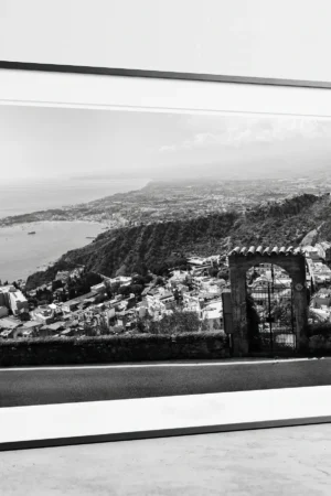 Framed Taormina Bay Sicily black and white digital wall art print by Mark Marsh, showing the freestanding stone archway and wrought-iron gate detail.