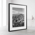 Mount Etna smoke plume black and white digital download print in a black frame, styled in a living room or study with concrete and stone textures, capturing the Sicilian volcano by Mark Marsh.