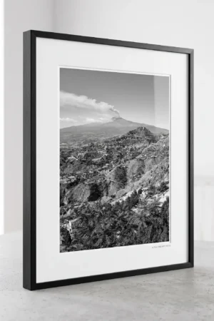 Mount Etna smoke plume black and white digital download print in a black frame, styled in a living room or study with concrete and stone textures, capturing the Sicilian volcano by Mark Marsh.