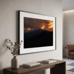 Framed colour printable art of Mount Etna at sunset after a storm, viewed from Taormina heights in Sicily—golden clouds above the volcanic silhouette, captured by Mark Marsh and displayed in a modern interior.