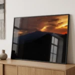 Etna golden hour colour digital download print in a black frame, styled in a living room with warm wood and neutral textures, capturing Sicilian twilight drama by Mark Marsh.