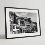 Framed black and white printable art of Via Madonna della Rocca in Taormina, Sicily—wrought-iron fencing, terraced stone houses, and Castello di Taormina above, captured by Mark Marsh.