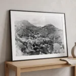 Framed black and white printable art taken from the Ancient Theatre of Taormina, Sicily—prickly pear cactus in the foreground, terraced villas below, and Peloritani mountains beyond, captured by Mark Marsh and displayed in a modern interior.