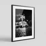 Cropped and framed Castelmola piazza black and white digital wall art print by Mark Marsh, showing the geometric mosaic tile floor and warm café interior light detail.